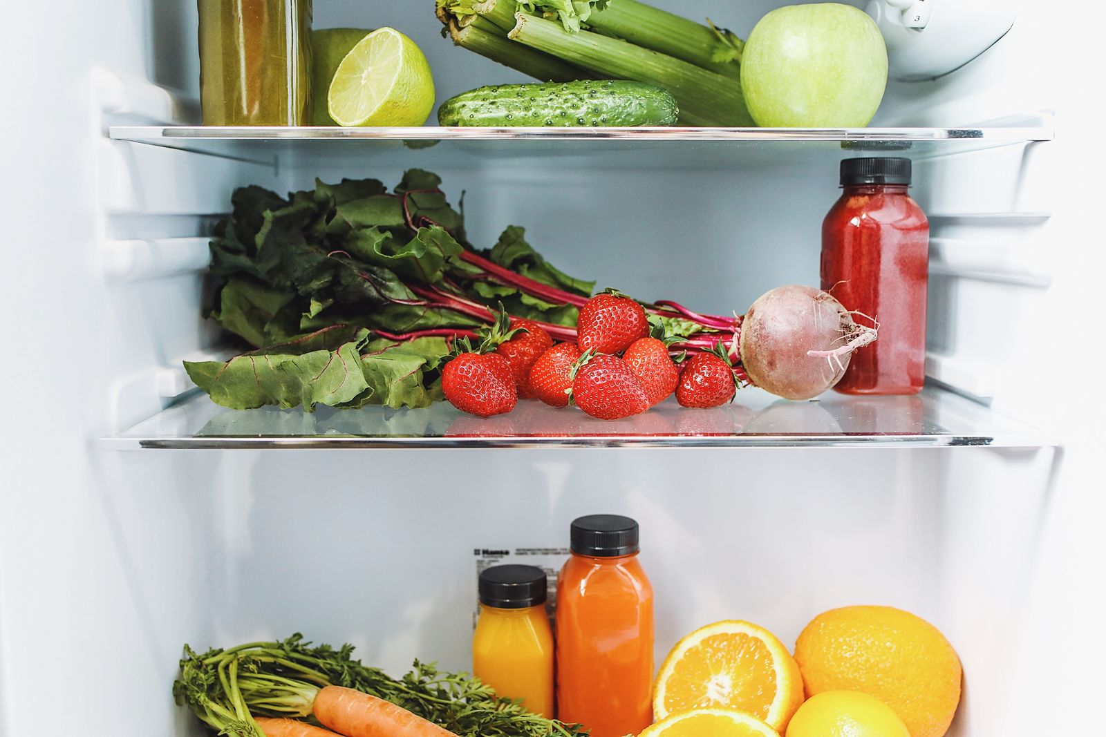 Gemüse, Obst und Säfte in einem geöffneten Kühlschrank